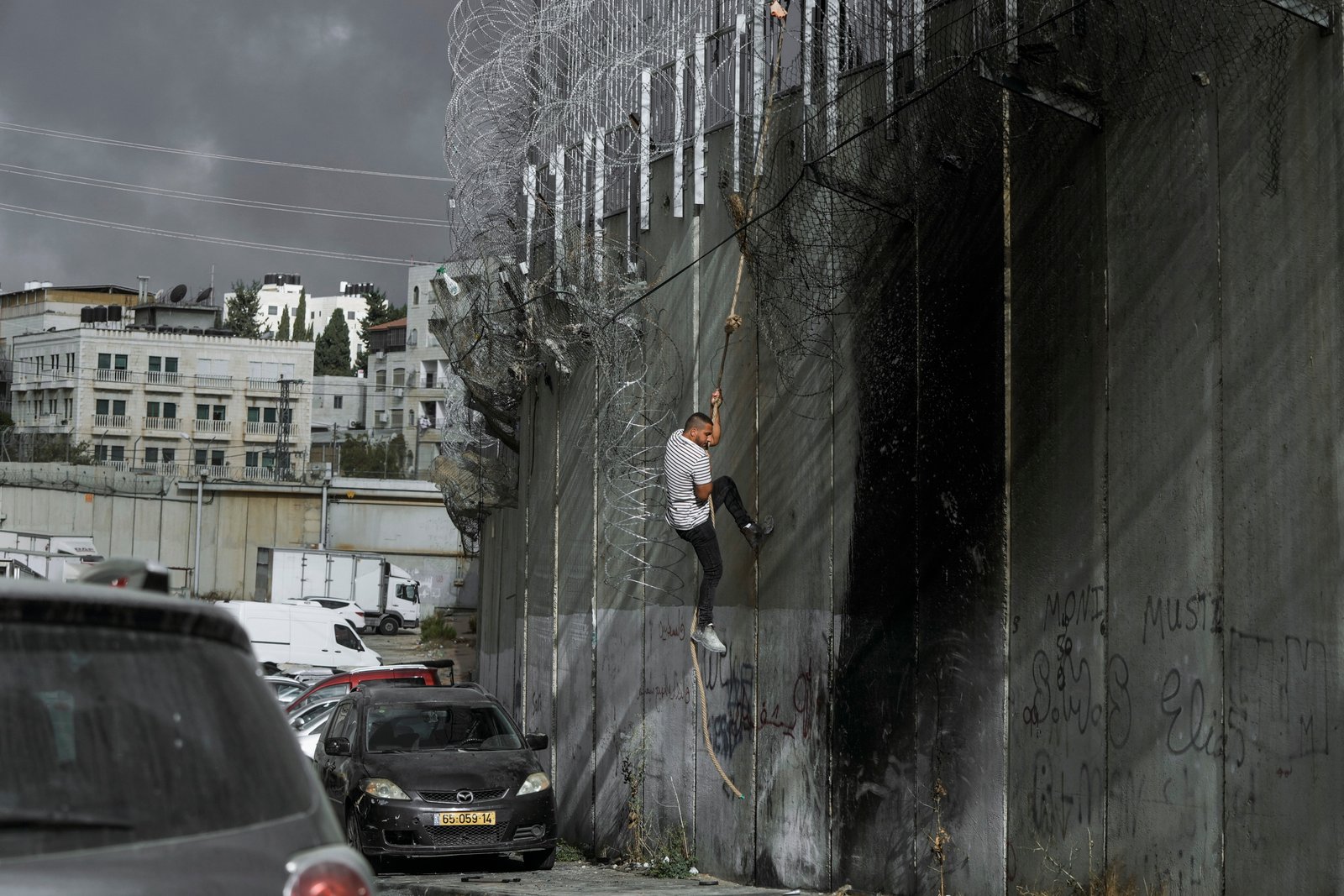 Palestinian man climbing separation wall at ar-Ram attempting illegal entry into Jerusalem