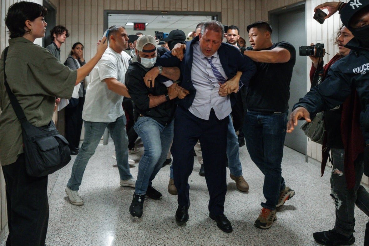 Brad Lander being escorted away during an arrest outside immigration court.