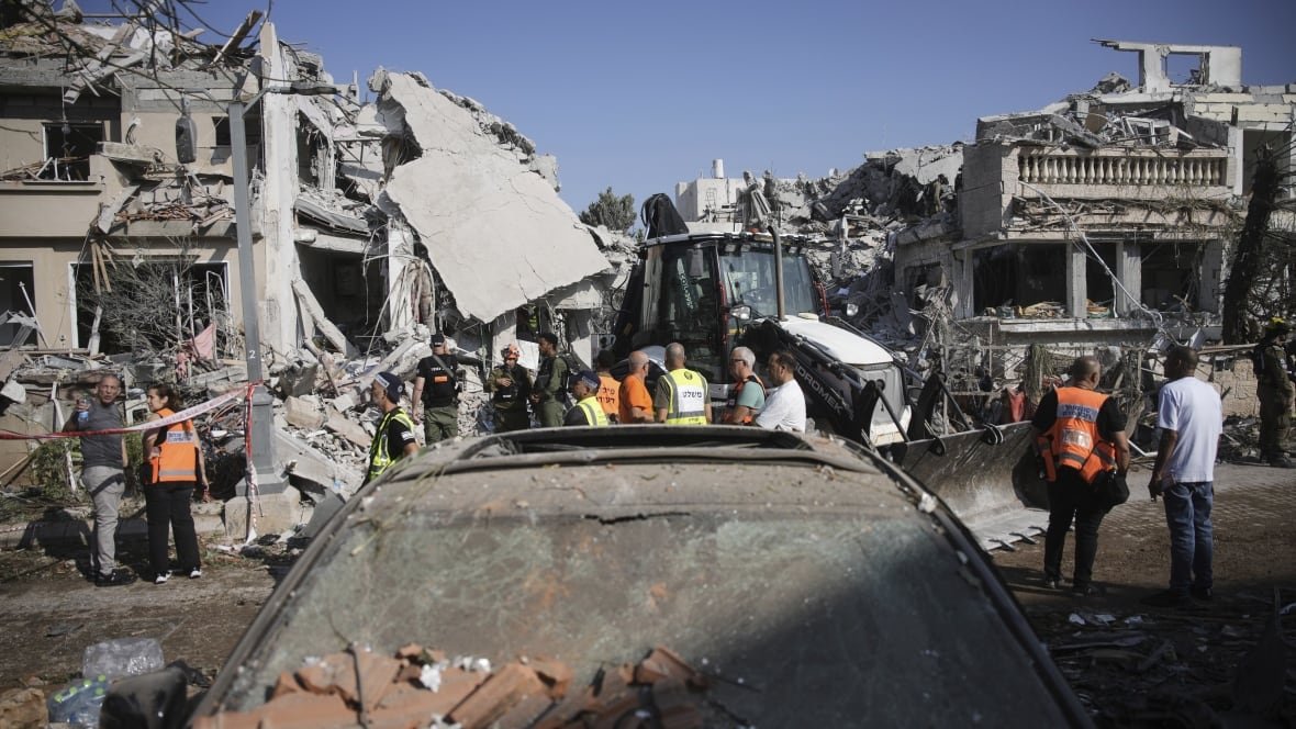 Israeli security personnel inspecting damage after missile strike