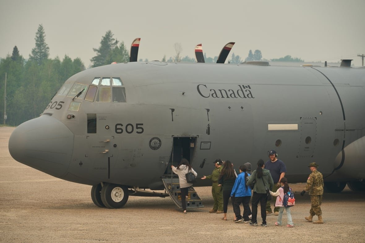 evacuees boarding military aircraft amid smoky skies