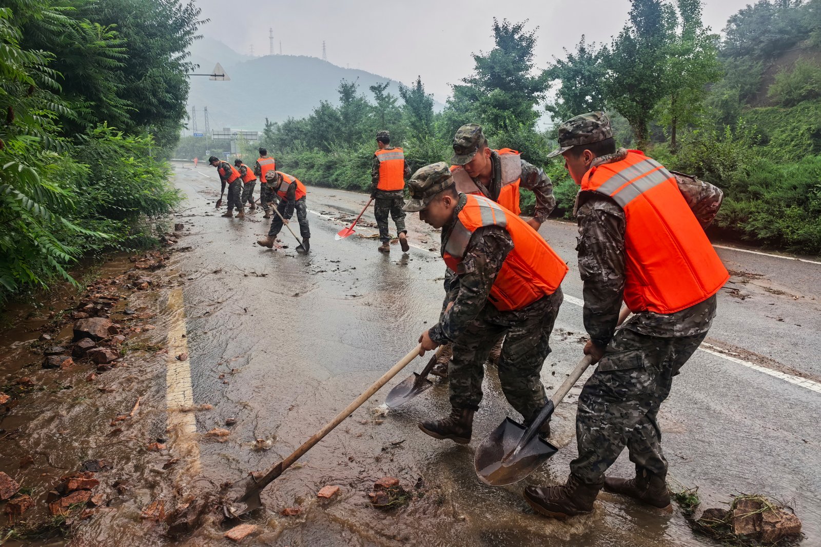 Chinese police force personnel clean up silt on a road in Miyun,north of Beijing