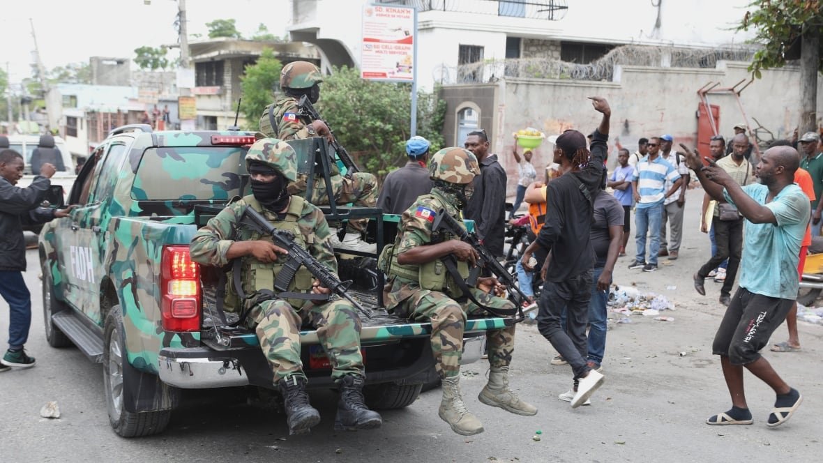 Armed individuals riding on truck through urban street