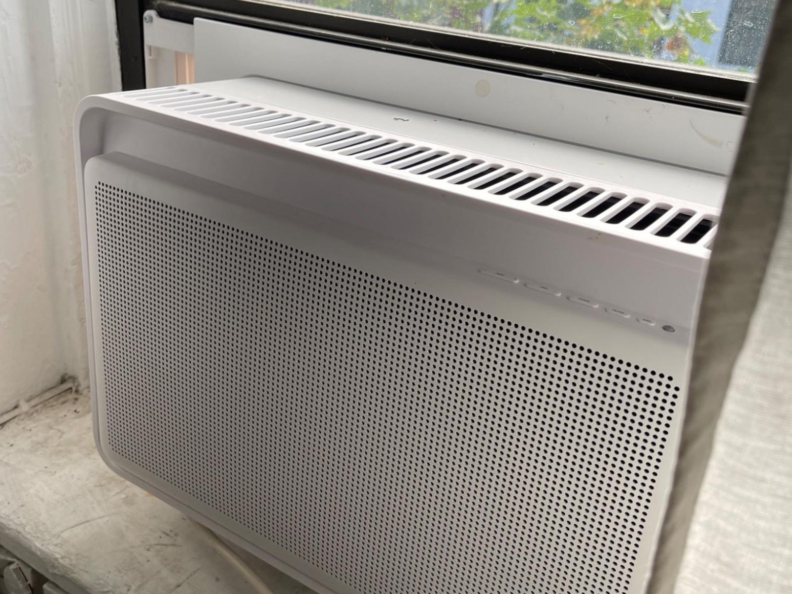 Air conditioner installed in window next to curtain