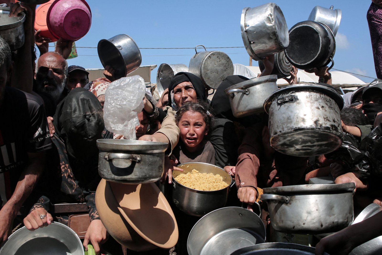 Displaced Palestinians receiving aid at community kitchen in Khan younis