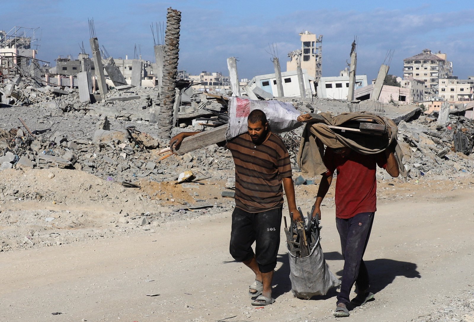Palestinians walk past rubble of destroyed buildings during Gaza ceasefire, October 15, 2025