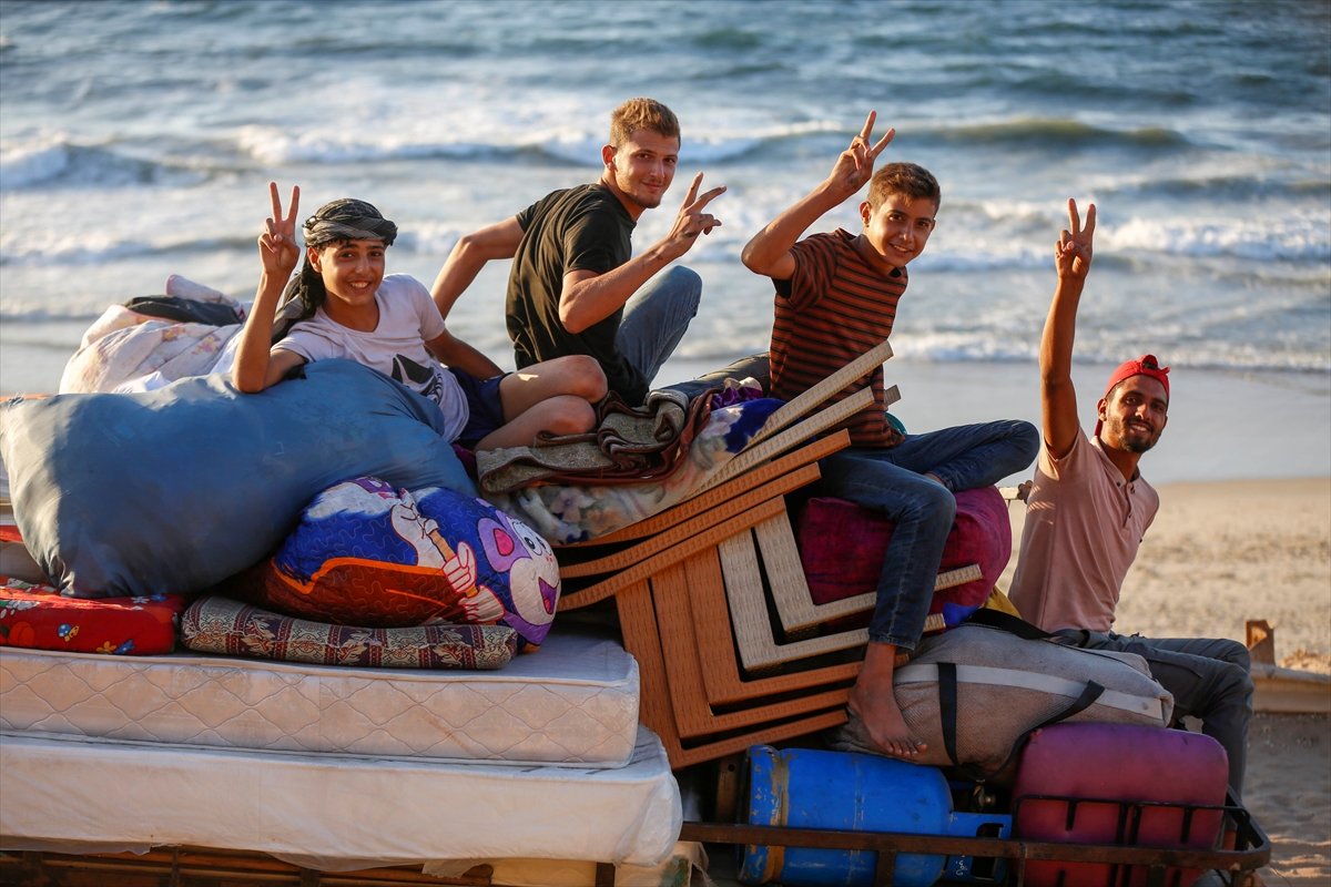 group of young men sitting on a cart by the beach making peace signs and smiling