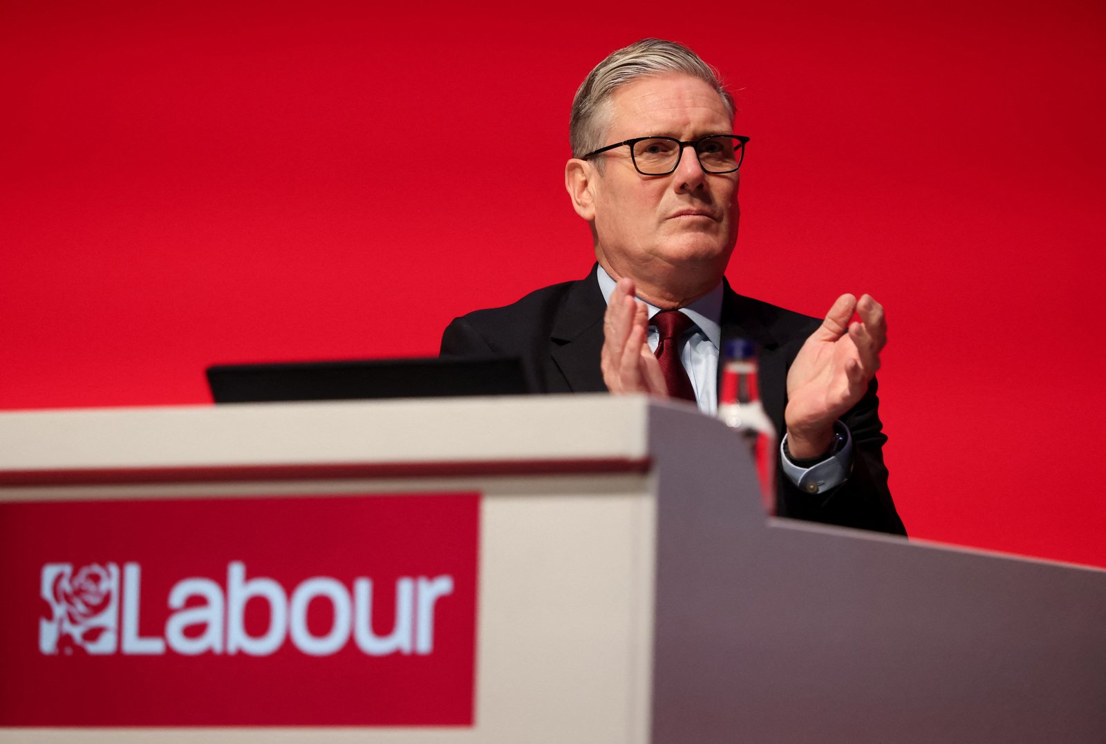British Prime Minister Keir Starmer applauds at podium