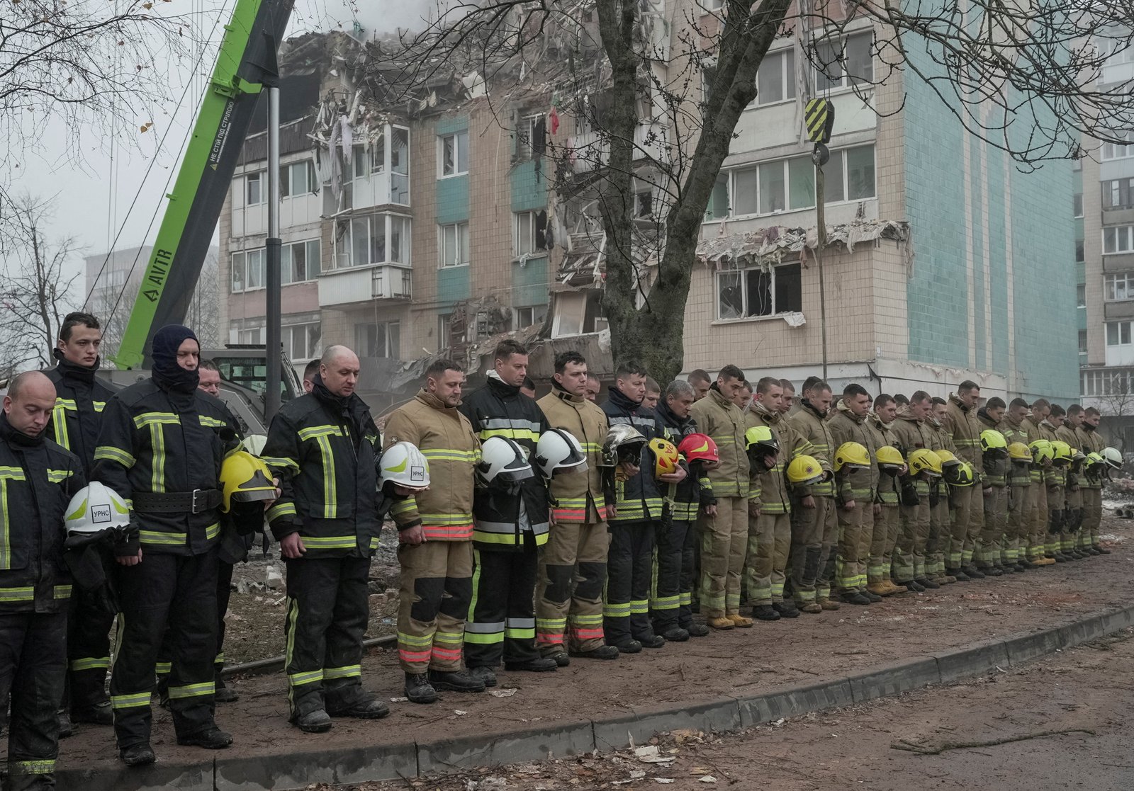 Emergency responders observe a moment of silence at the site of a missile strike on an apartment building in ternopil, Ukraine