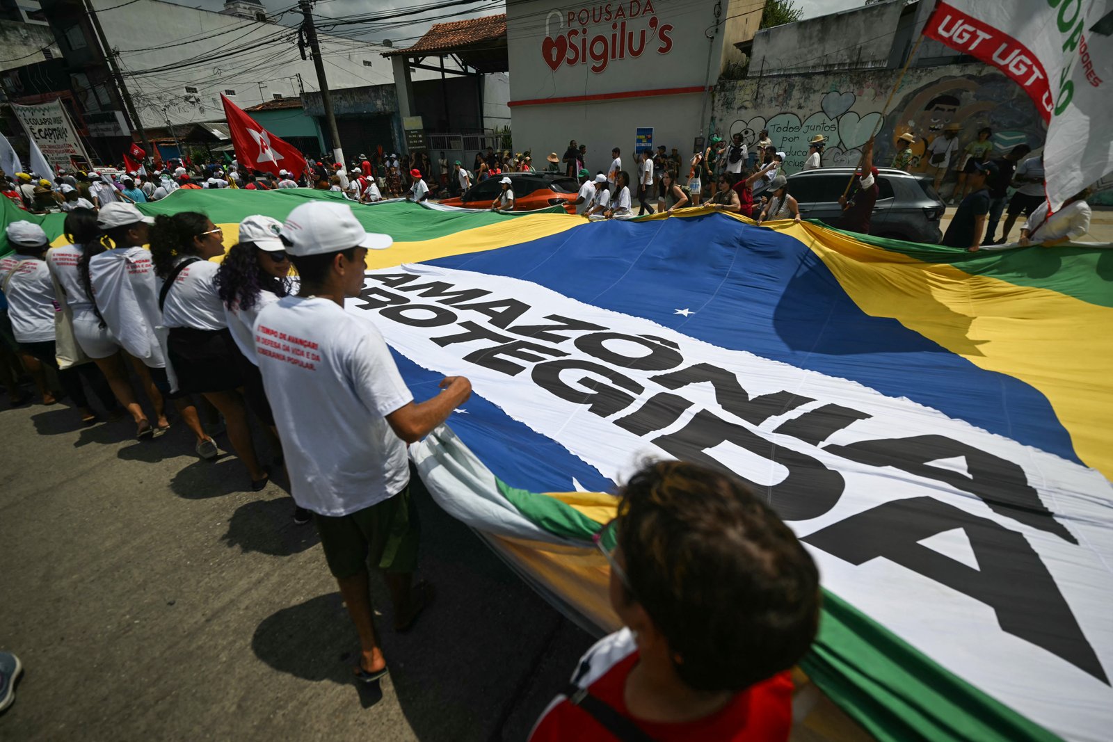 Demonstrators holding large Brazilian flag reading 'Protected Amazon' during Great People's March in Belem