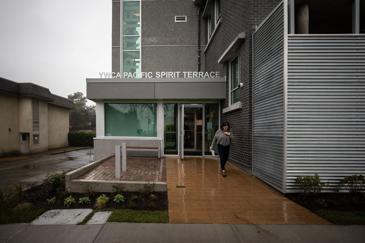 Woman leaving a building marked 'YWCA Pacific Spirit Terrace'