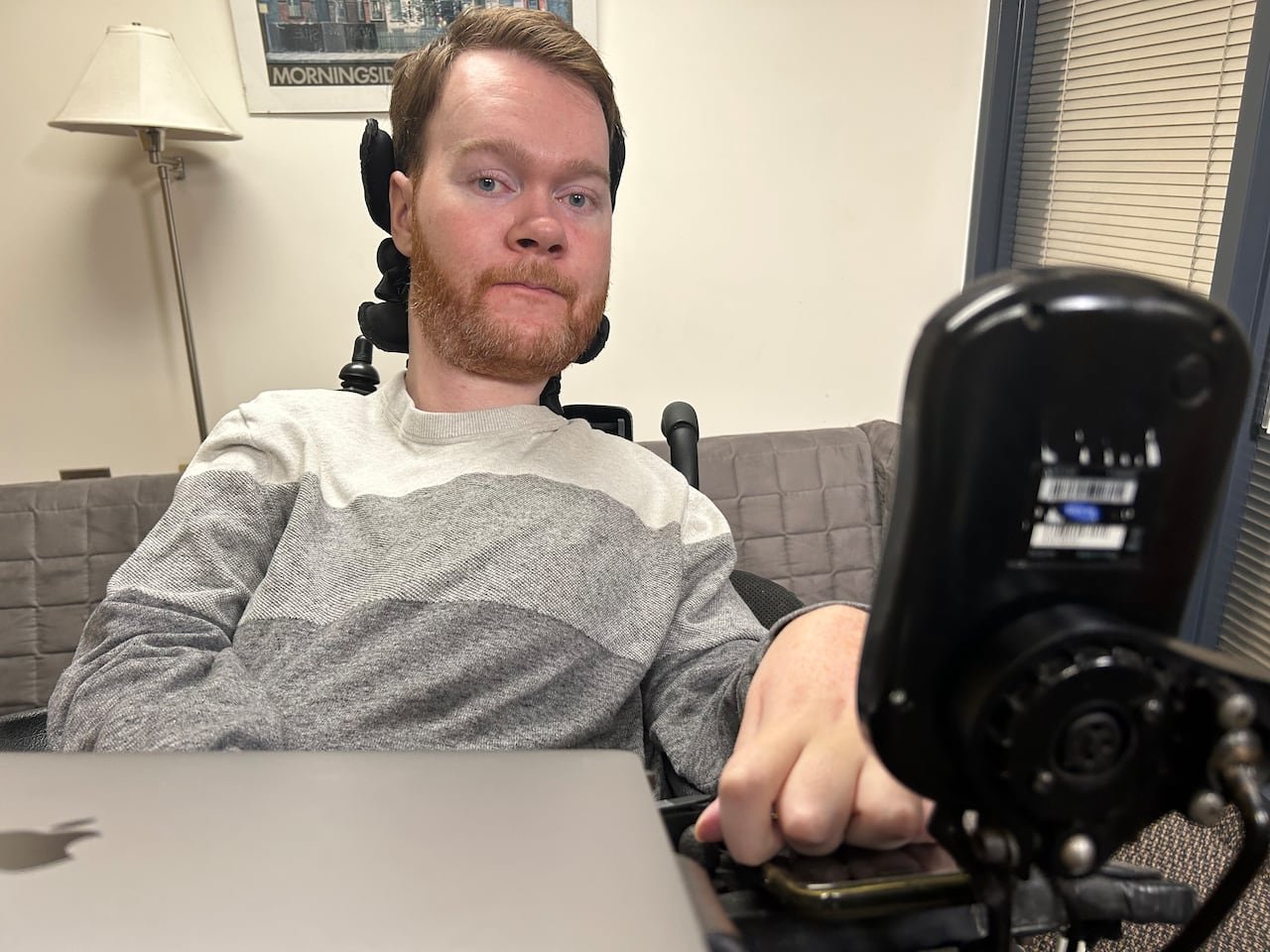 Jeremy Bray seated in wheelchair using laptop