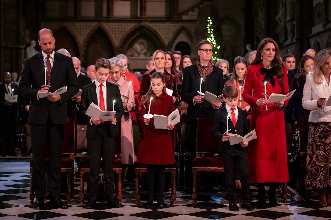 Royal family attending Christmas carol service holding candles.