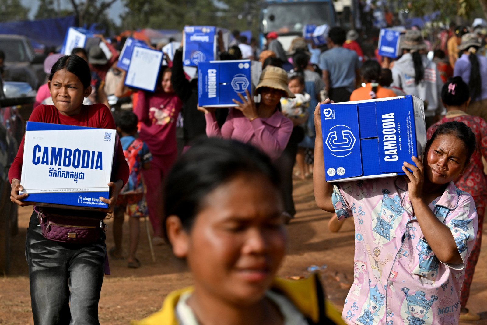 Displaced people carrying water boxes at a temporary camp in Oddar Meanchey province amid Cambodia-Thailand clashes