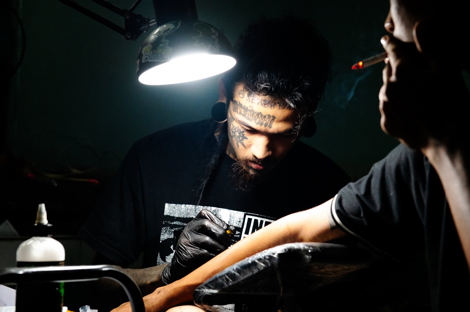 Ng La tattooing another myanmar exile inside his punk bar