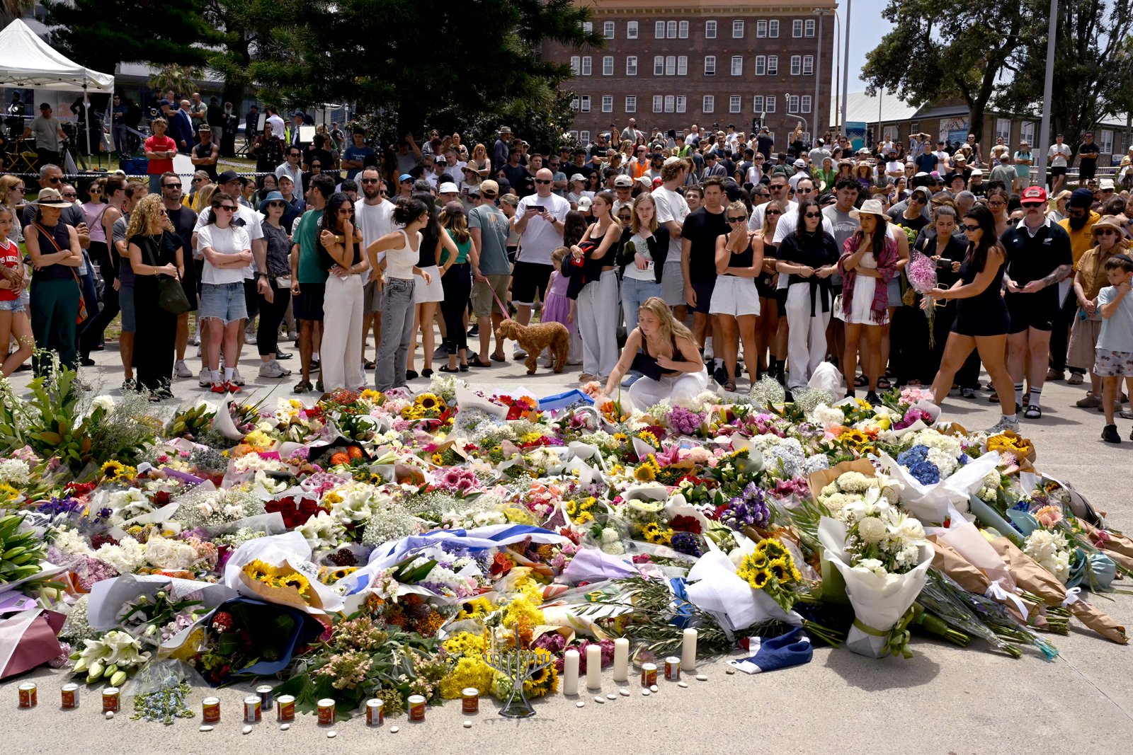 Mourners gather by floral tributes at Bondi Pavilion in Sydney