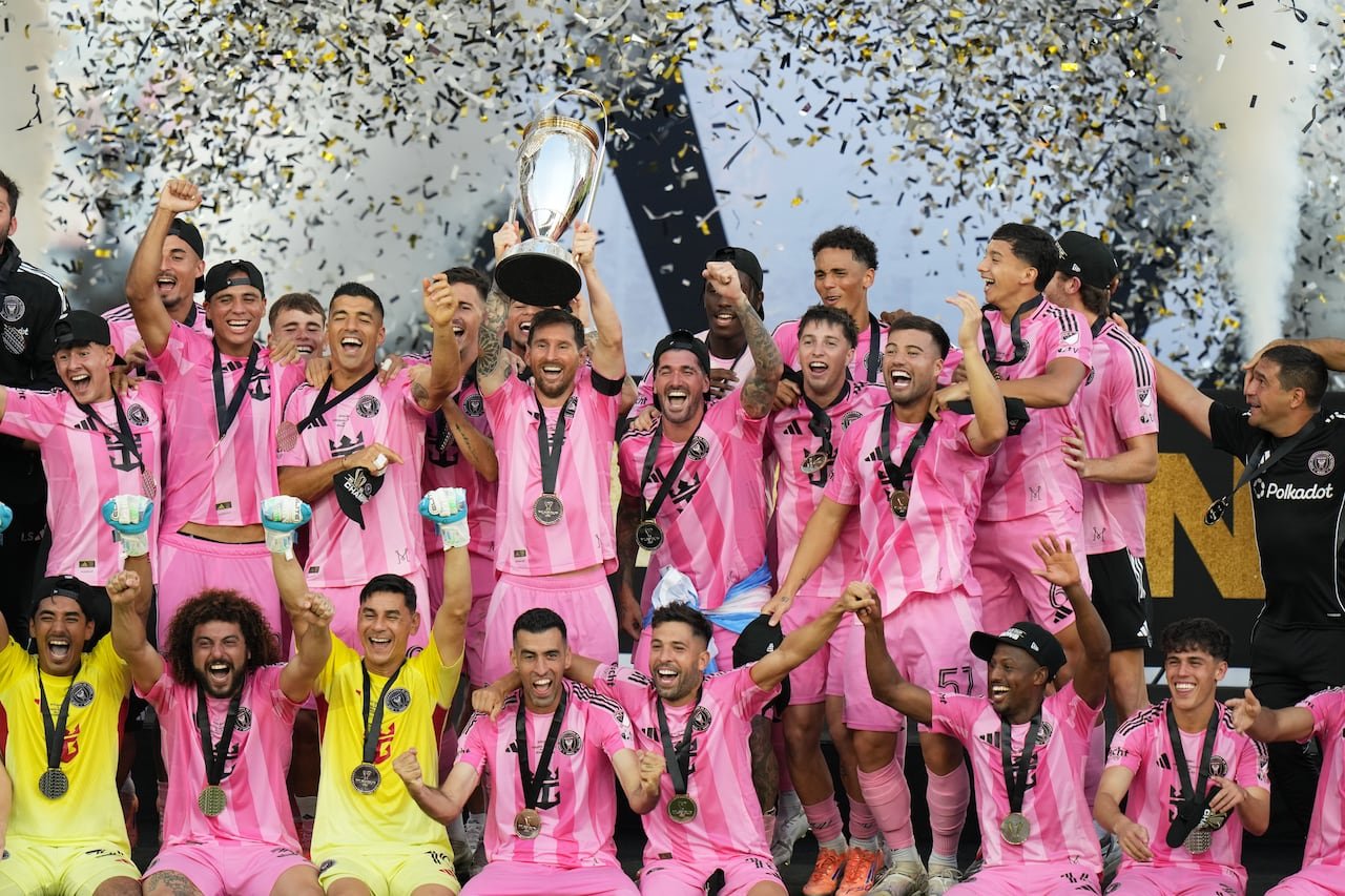 Inter Miami soccer team in pink jerseys celebrating MLS Cup victory with trophy