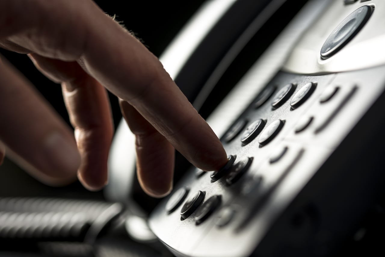 Close-up of hands holding telephone receiver representing scam calls