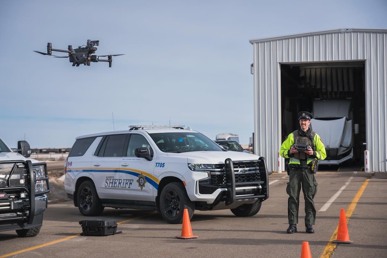 Law enforcement officer operating surveillance drone near vehicle