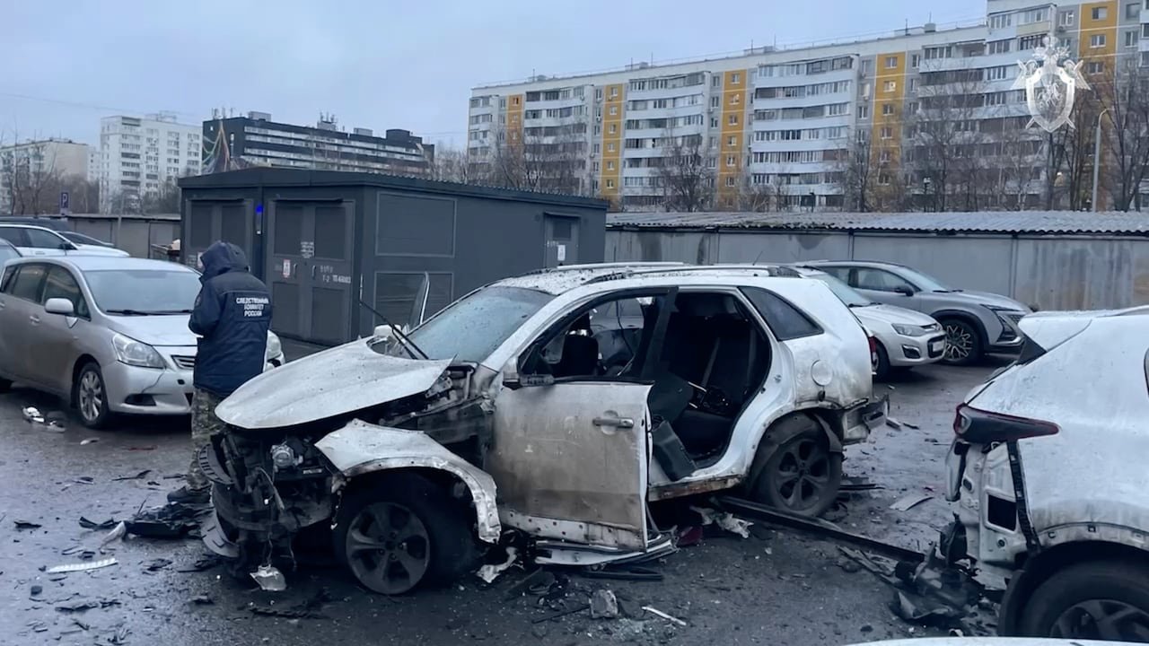 Damaged white car with blown-out door after explosion