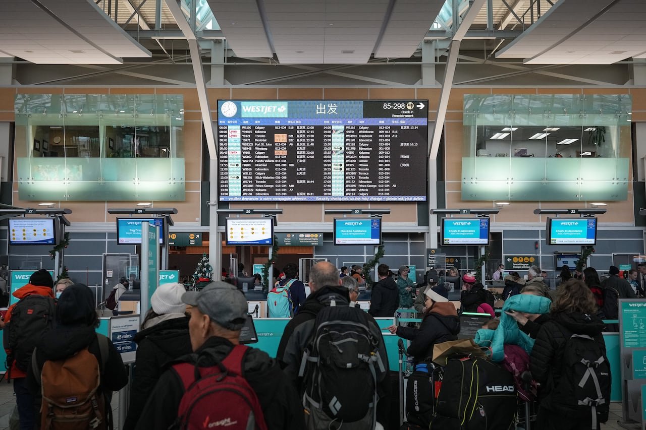 Travelers dressed warmly waiting inside a bustling Canadian airport terminal