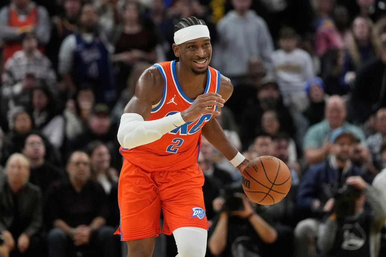 Oklahoma City guard Shai Gilgeous-Alexander smiling while dribbling during a game