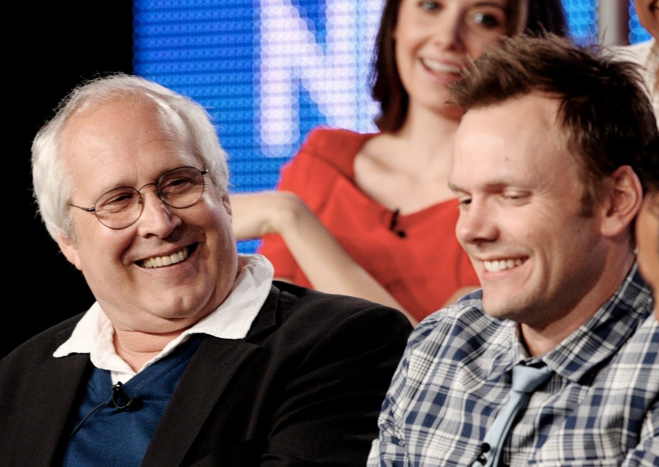 Chevy Chase laughing alongside Joel McHale during panel discussion
