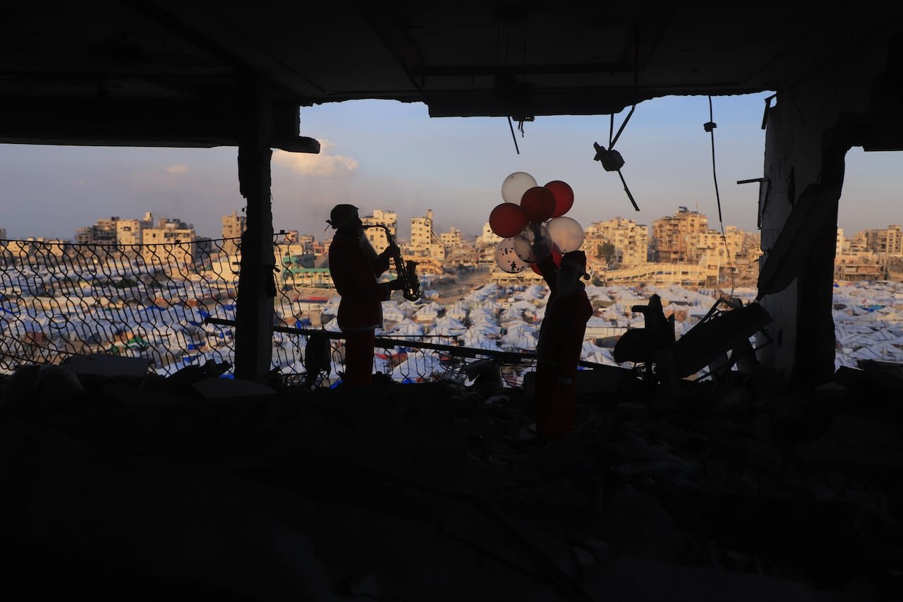 Silhouettes playing music overlooking tent city at dusk