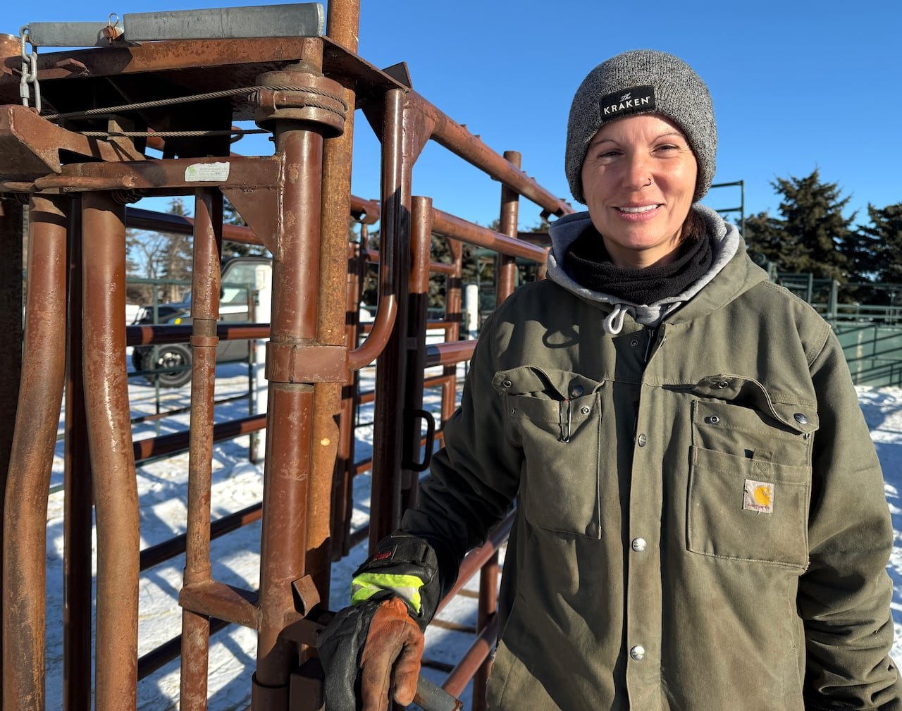 Woman dressed warmly leaning against cattle chute outdoors