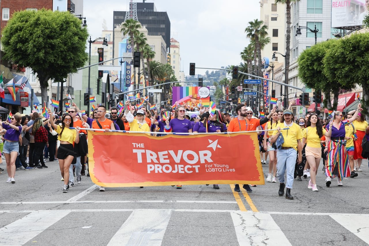 Participants marching with rainbow flags supporting LGBTQ+ youth