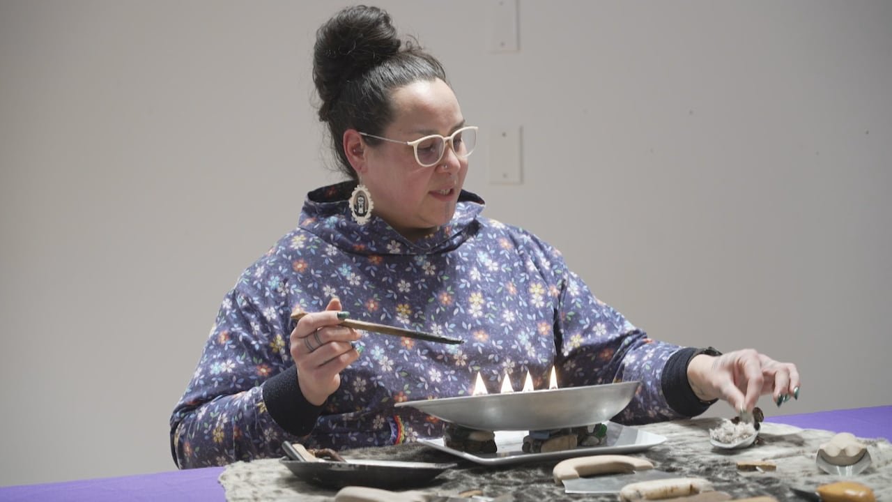 Woman lighting traditional oil lamp during ceremony