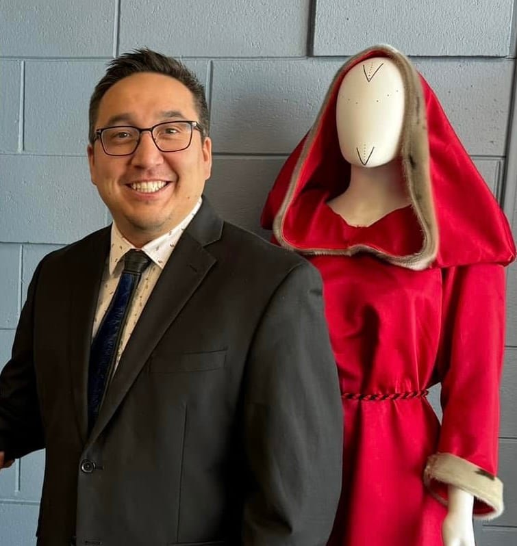 Man standing next to mannequin wearing red hooded garment