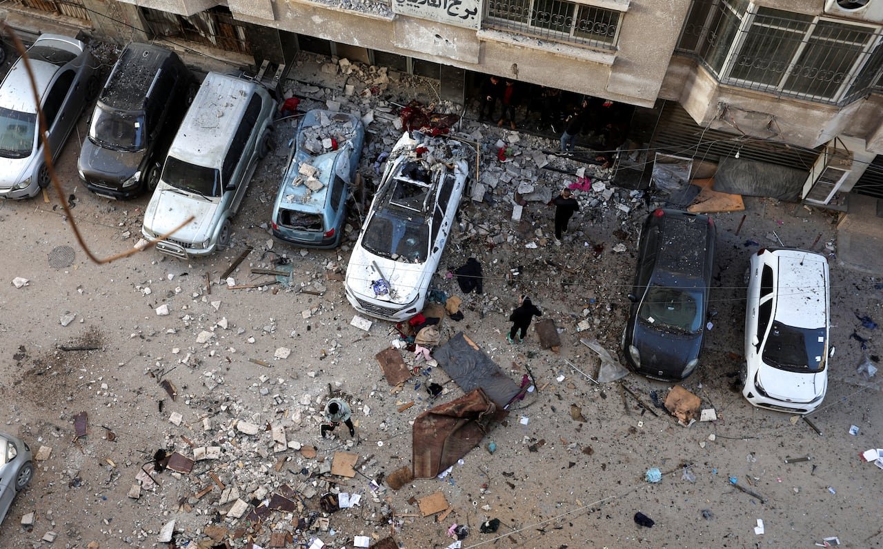 Aerial view showing destruction outside damaged buildings with rubble scattered around.