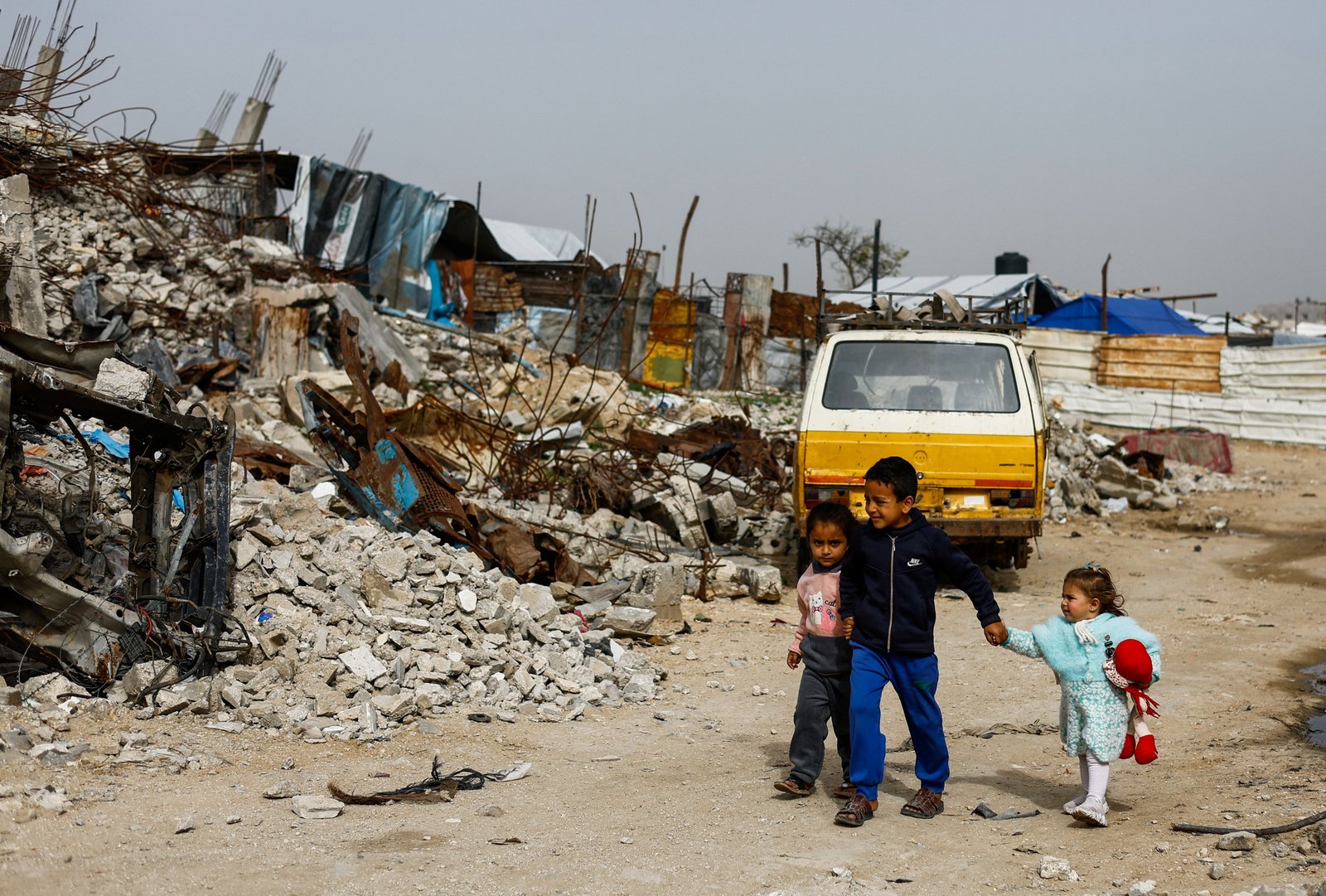 Children walking past destroyed buildings after conflict damage in Gaza City