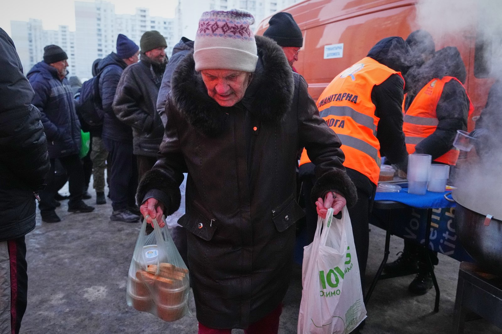 An elderly woman carries her bags out of a hot food distribution point during a power outage caused by russia's repeated air strikes on the country's power grid,in Kyiv,ukraine