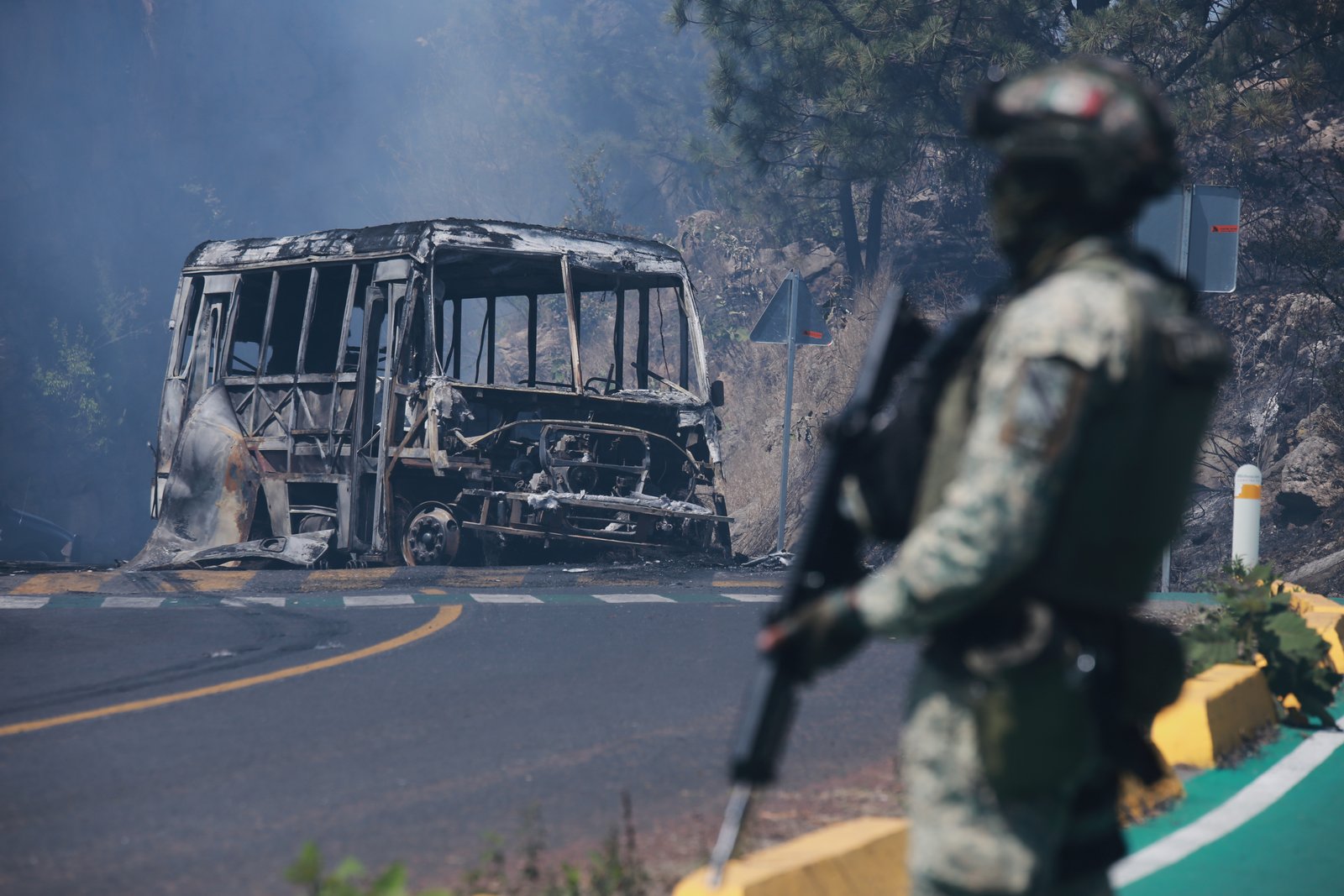 Soldier guarding charred vehicle after violence following El Mencho's death