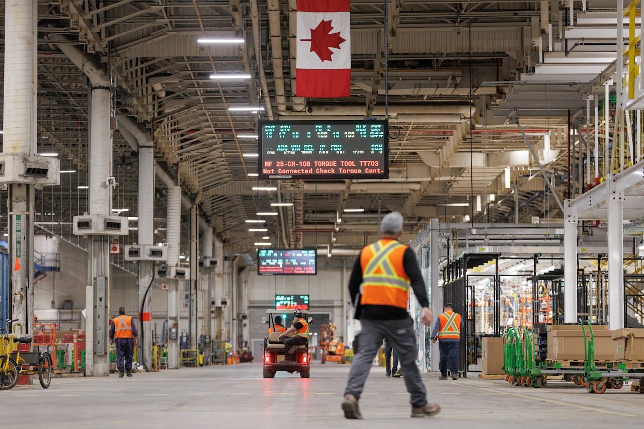 Workers assembling components inside a modern automobile factory