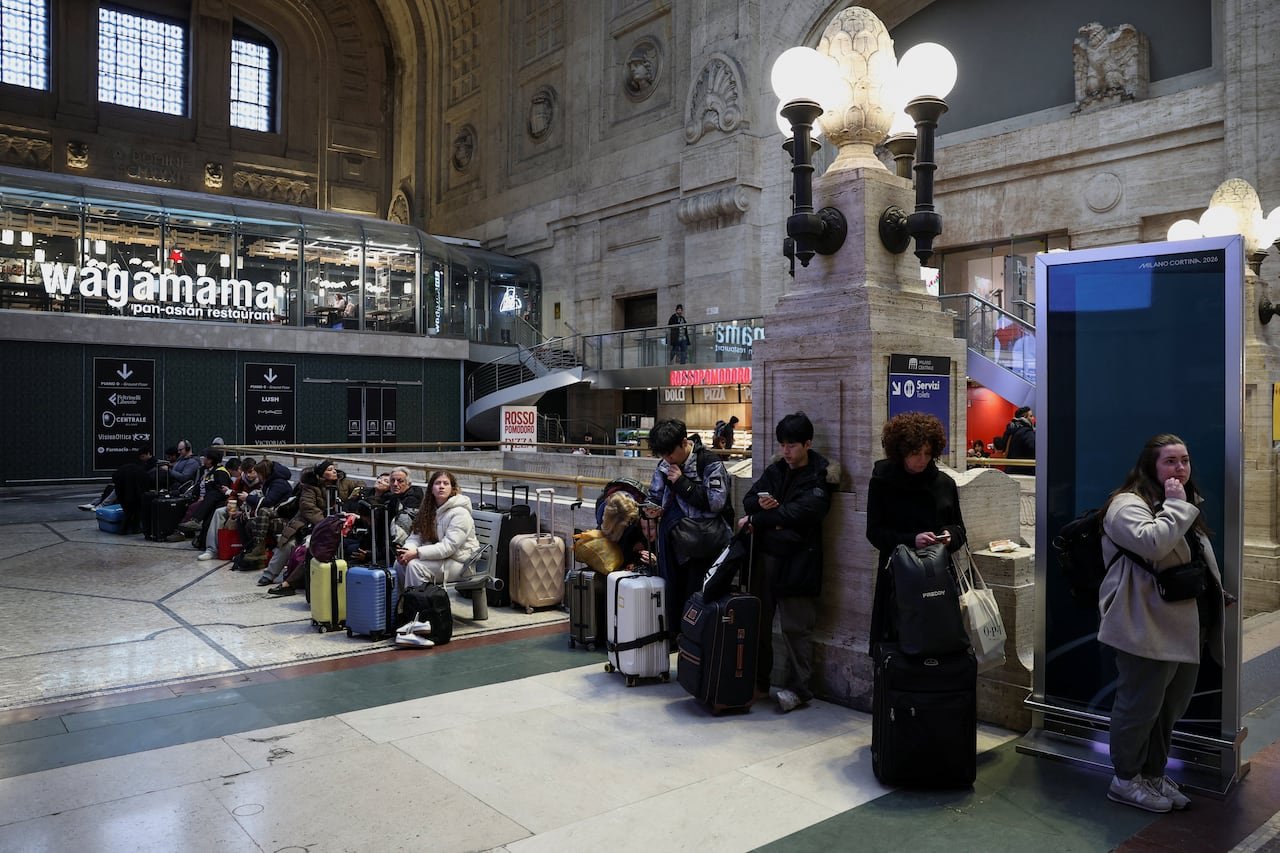 Crowded European train station interior with travelers waiting among luggage