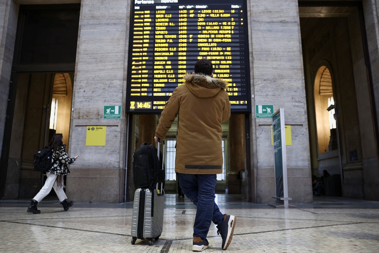 Passenger checking delay data board at Milan train station