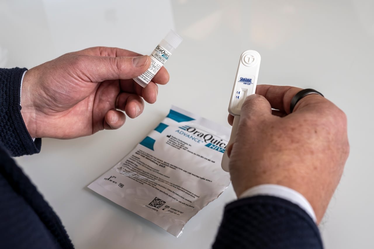 Close-up image showing hands holding an oral swab kit used ⁣for rapid self-testing