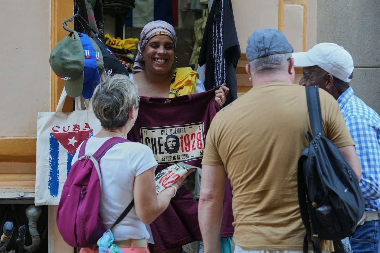 Street vendor selling souvenirs near tourists exploring historic Havana streets