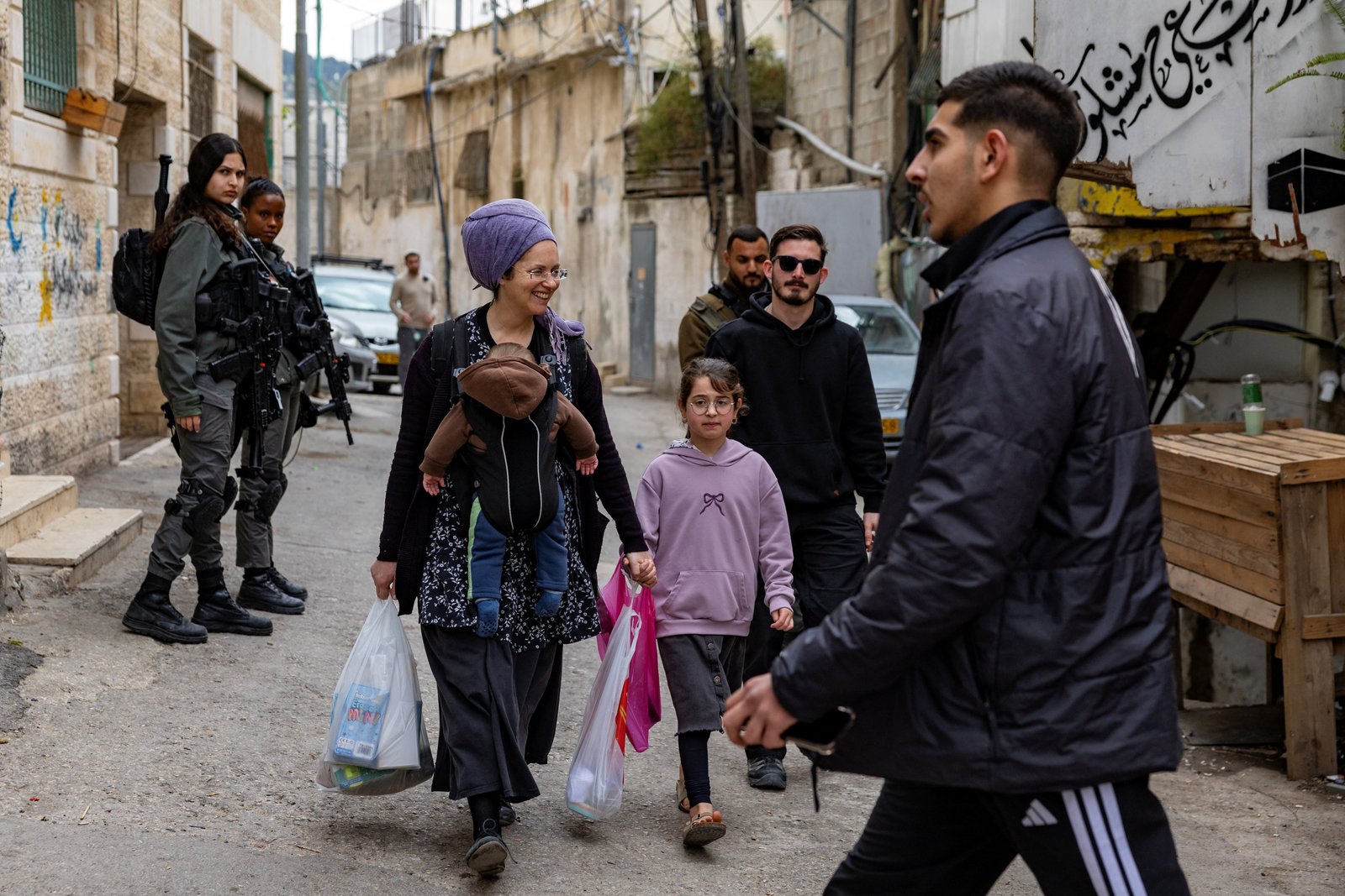 Israeli settlers walk past Israeli police after eviction operations in Batn al-Hawa area