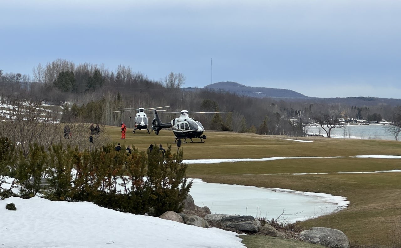 Two police helicopters parked near shore after rescue
