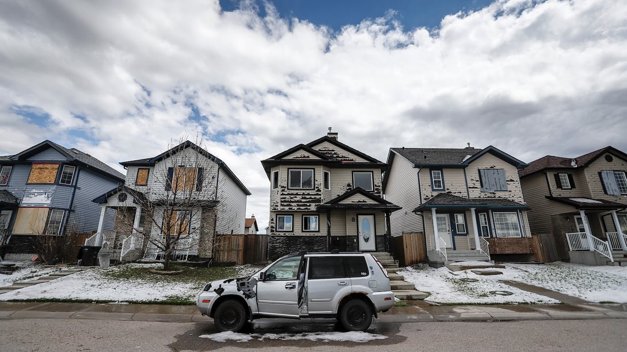 SUV parked outside homes damaged by hailstorms.