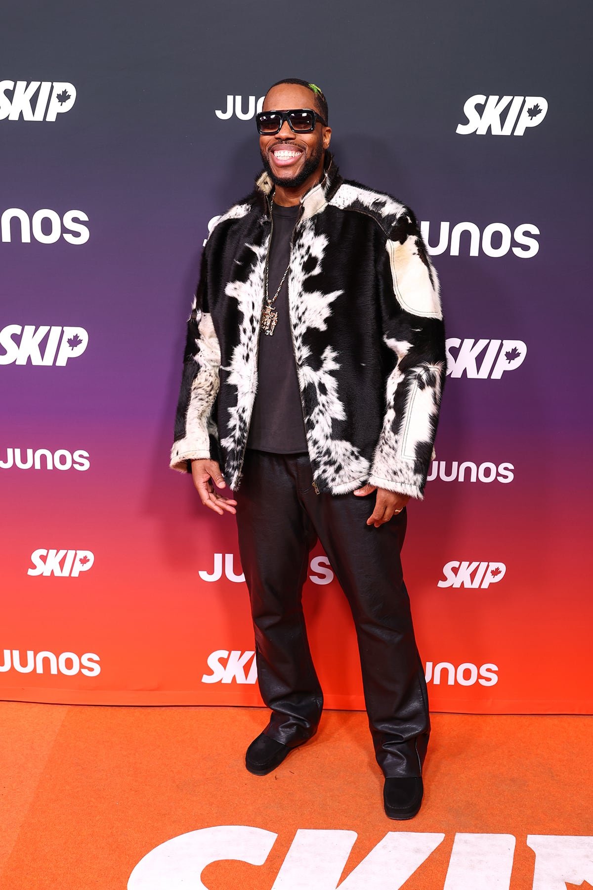 Kardinal Offishall posing on orange carpet wearing cow print jacket leather pants sunglasses pendant necklace