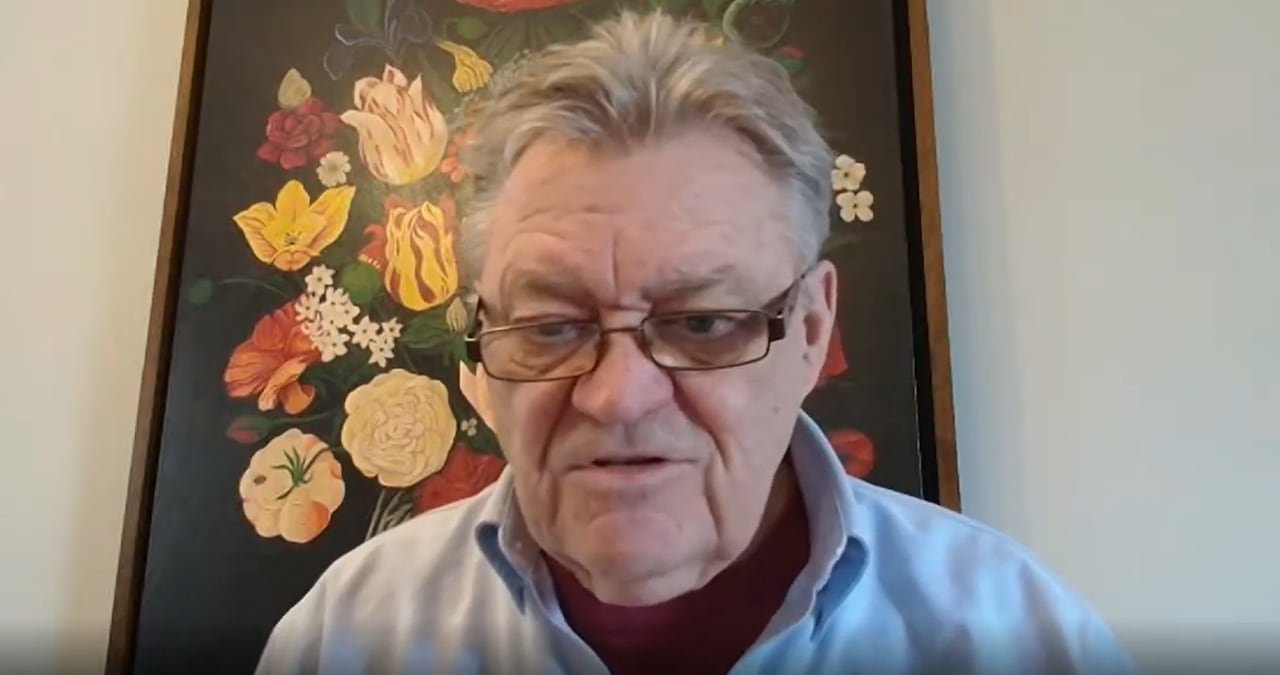 Older man wearing glasses participating in video call.