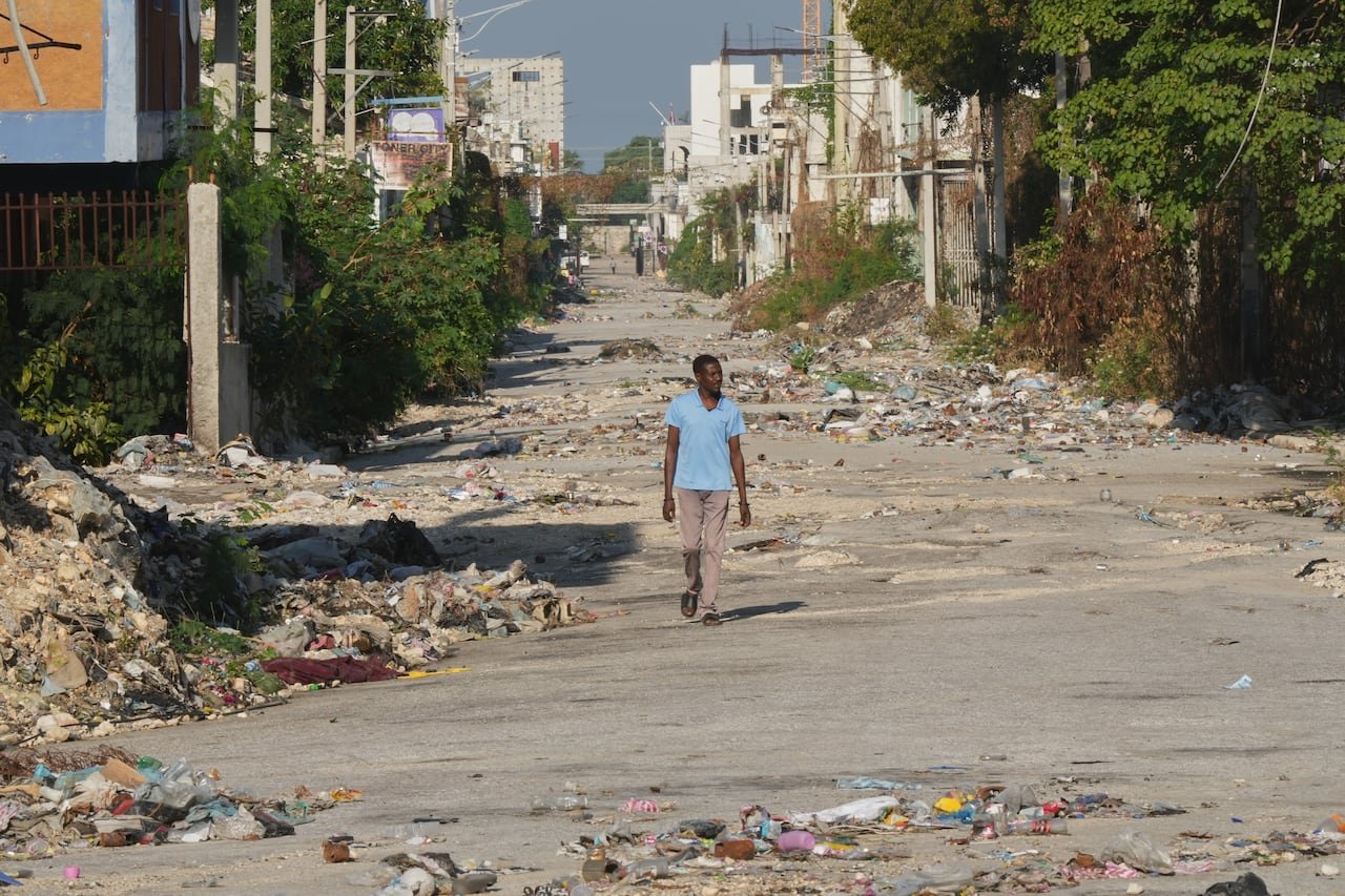 Man walking through debris-strewn street controlled by gangs downtown Port-au-Prince.