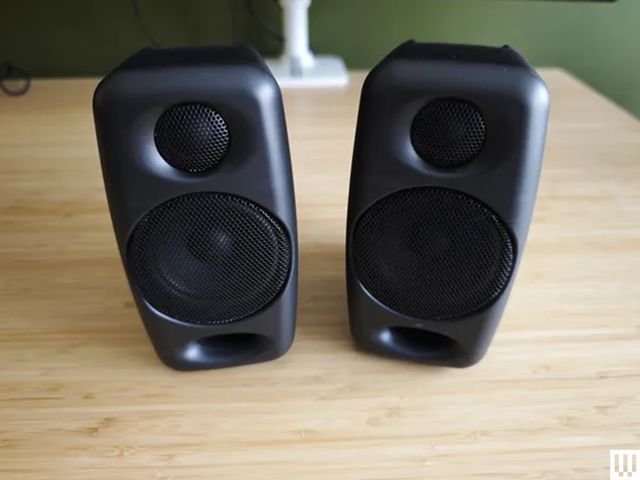 Pair of black rectangular IK Multimedia iLoud Micro Monitor speakers angled upward on wooden desk