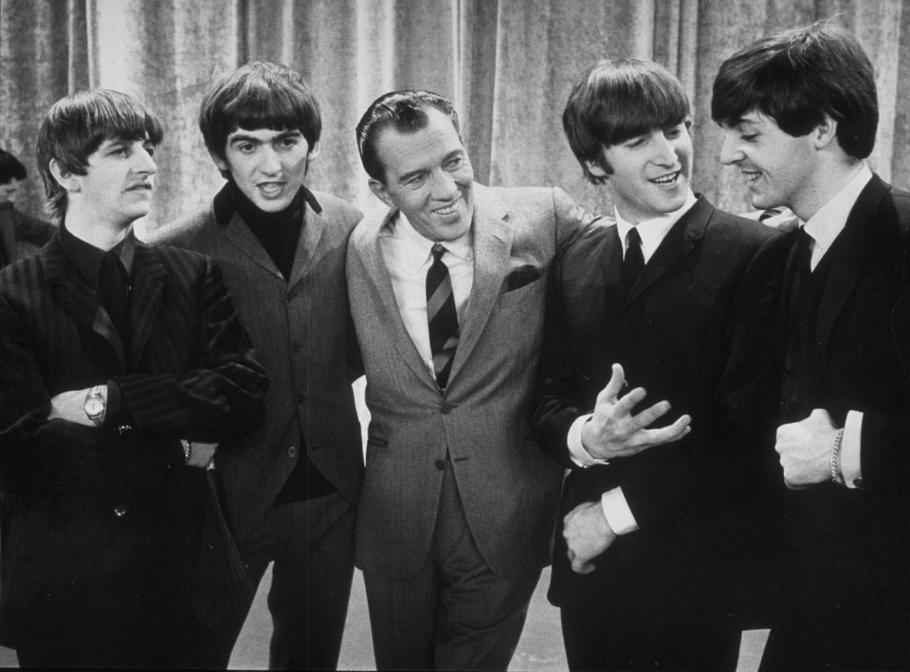 Ed Sullivan standing center stage surrounded by The Beatles during historic TV appearance