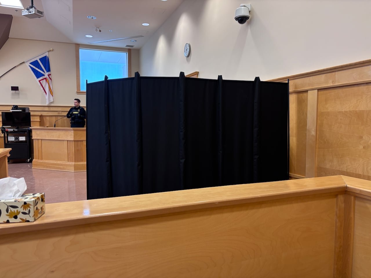 Courtroom scene behind black curtain protecting witness identities.