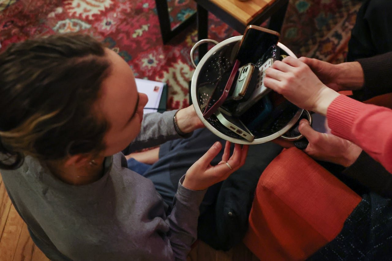 Participants placing smartphones into a bowl during an offline event
